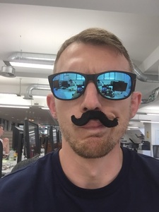 In an office wearing a fake moustache